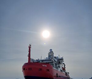 A red icebreaking ship parked in ice