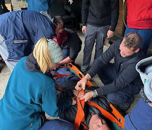 Image of 8 people working together to put person into stretcher