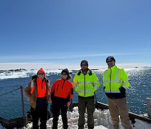 Four people standing at the Casey wharf with the water behind them