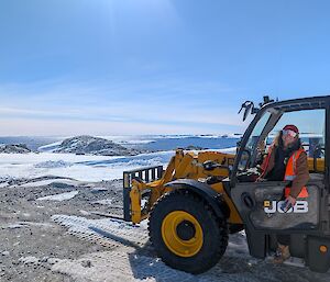 Supply officer Charlotte sitting in the JCB with the bay in the back ground