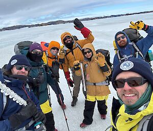 A group of smiling expeditioners cheering with their arms in the air