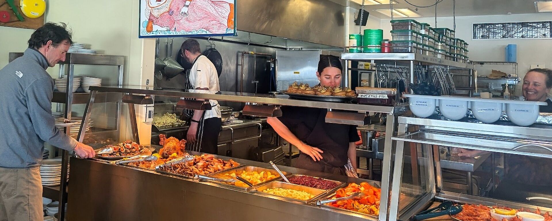A buffet selection in a bain marie with a sign above featuring Miss Piggy an the phrase 'A Feast for Your Senses'
