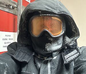 A person in black outdoor gear and snow goggles