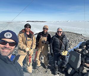 Four smiling people stand on ice