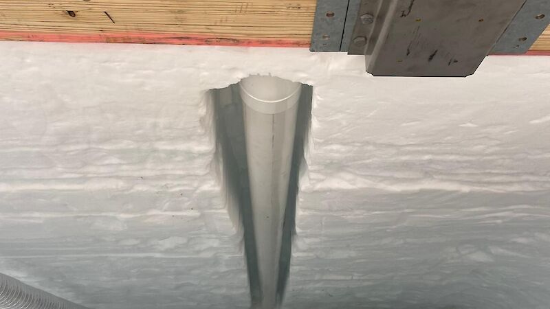 A wooden frame with a pipe going down in the ice