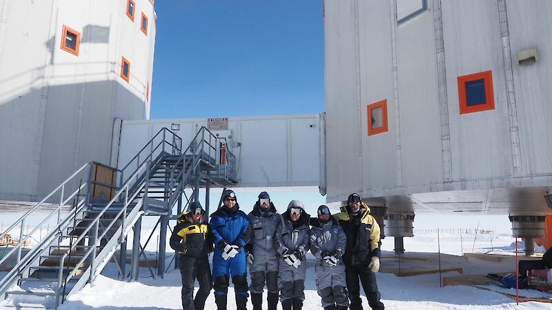 A group of people standing in front of two Antarctic buildings
