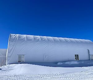 A white tube soft shell building under a blue sky on the snow