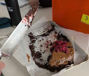 A mostly eaten chocolate case with a knife