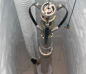 A silver metal instrument in a deep ice hole.