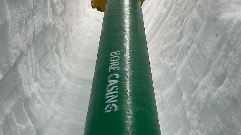 A length of green pipe going down into a borehole