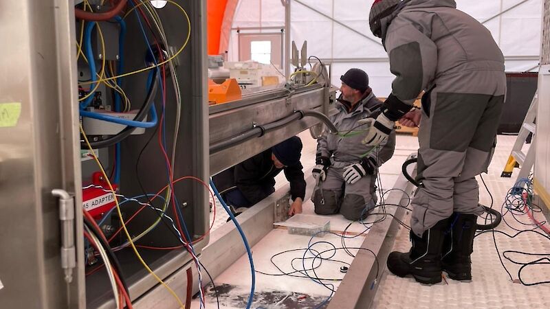 Two people huddled over wiring and the frame