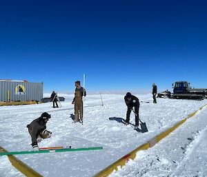 People flattening and levelling snow inside a wooden fram