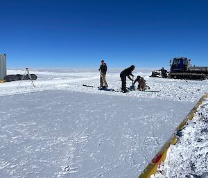 Half an area inside a wooden square frame has flattened snow, the other half still rough