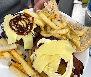 A plate with a chicken burger, cheese and chips