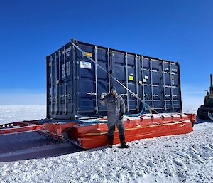 Joel Pedro stading beside a shipping container on a sled.