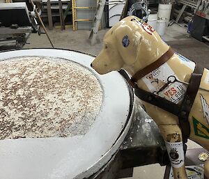 A plastic Guise Dog's Australia dog peers over a round incinerator door that has recently been repaired.