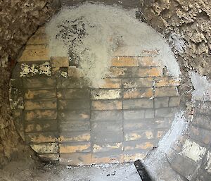 The back wall of a round incinerator lined with cream coloured bricks and not yet rendered.