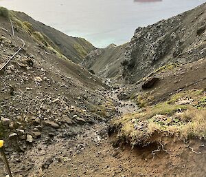 Looking down Gadgets Gully towards the ocean where a large orange ship sits.
