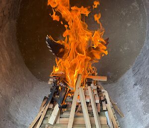 A wooden model of an Albatross is alight on a pile of wood inside the incinerator as a first trial burn