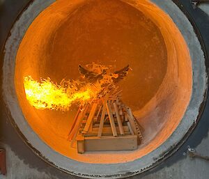 A well burning model of a wooden albatross inside the incinerator with a golden flame