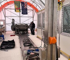 View inside the ice core drilling tent showing the drill tower at the front and the large winch at the back, with a long metal channel between.