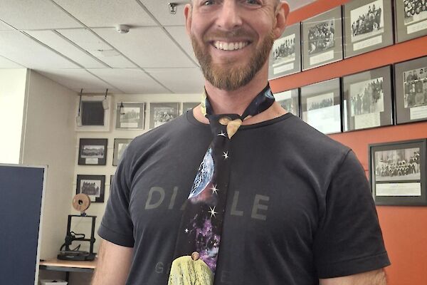 Josh standing in the foreground, proudly wearing his space tie, the lower lounge area in the background.