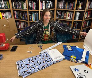 Lisa the Fix it Fairy at the library desk with her sewing machine and donning her fairy wings in the foreground, the library shelves in the background.