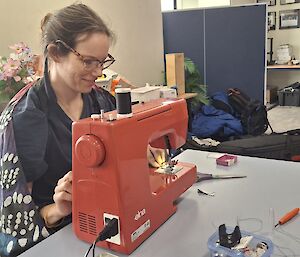 Lisa at the sewing machine, conducting her fix it fairy magic in the foreground, the lower lounge area in the background