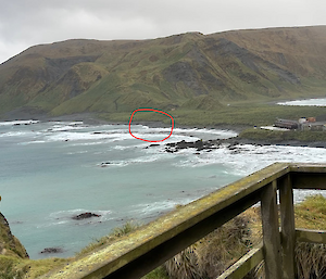 A view from a lookout to lots of whitewash on a coastline. Landing Beach has been circled in red to show the swell conditions.