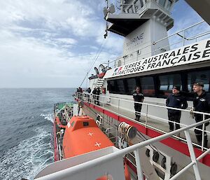 People standing on the deck of a ship looking towards land