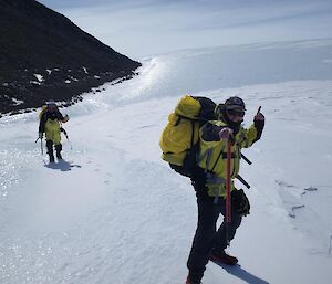 Two people on an icy slope with a big black mountain behind them