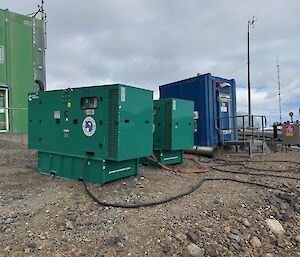 The large green generators sit in front of a small blue services building