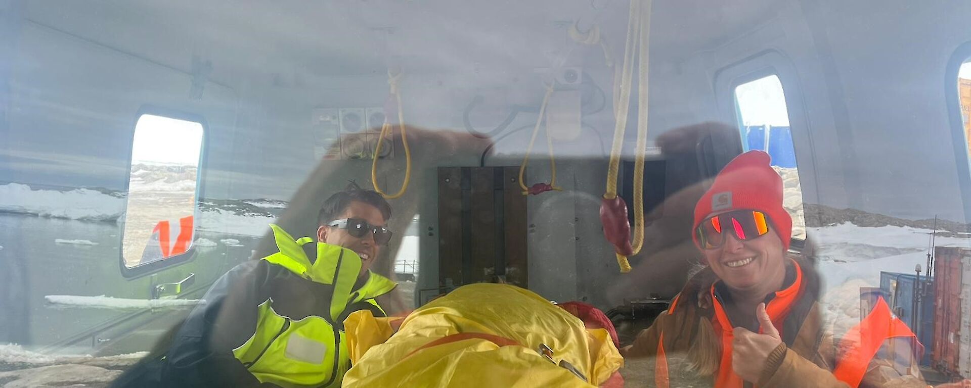 Through the windscreen of the Hagglund, Jess is seen wrapped in a bivvy bag for warmth, next to trusty SAR member, Cliffy for reassurance