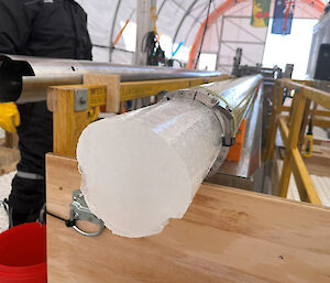 Part of an ice core hanging out of the end of the drill barrel.