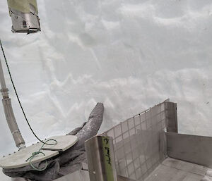 A metal channel installed in an ice slot beside the drill borehole, to catch anything that might fall into the ice slot.