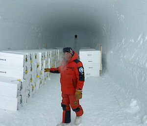 A man standing in a tunnel filled with white boxes containing ice cores.