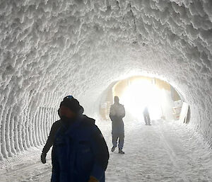 People walk through a tunnel built under the ice in Antarctica.