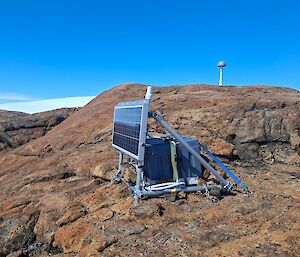 Scientific equipment with a large solar panel in front stands on a rocky mountaintop