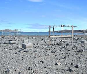 A number of antennas sit in a rocky landscape next to a blue body of water