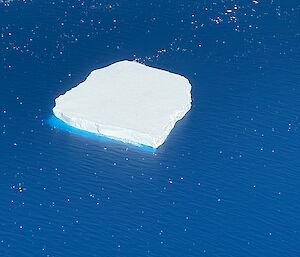 Aerial view of a tabular iceberg in a blue ocean