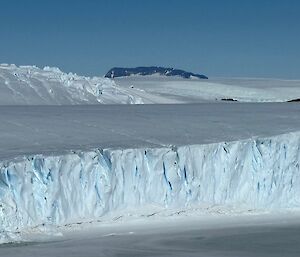 View of ice cliffs with a rocky mountain range in the distance