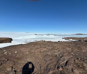 View of ice cliffs in the distance with a rocky foreground