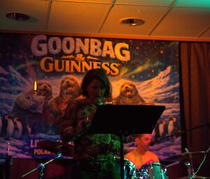 A dimly lit room with a person singing at a music stand