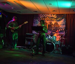 A dimly lit room with musicians playing guitars and drums