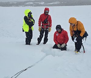 A group of people in the snow and ice, using search and rescue equipment
