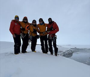 A group of people standing arm in arm on an ice covered hill