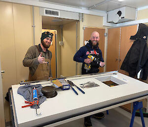Two men working on fixing a small window on a door that is resting on two saw horses.