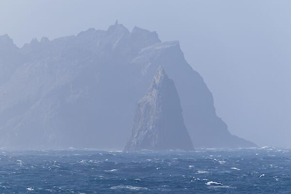 A rocky island with a pointy rock in the foreground