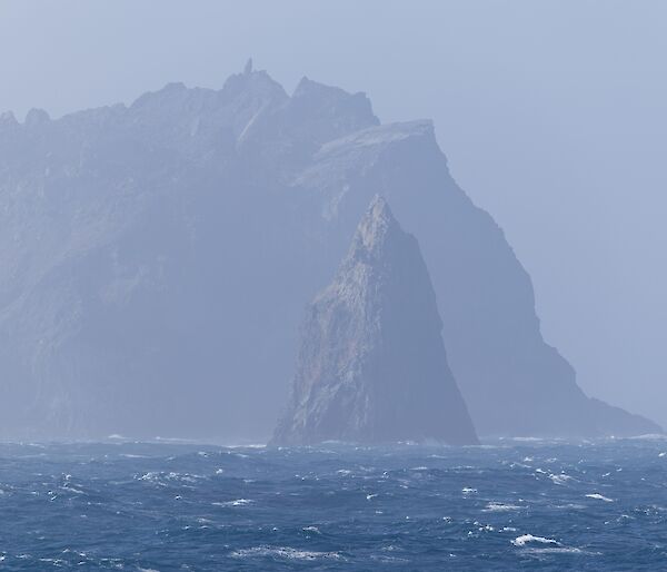 A rocky island with a pointy rock in the foreground