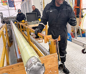 A man stands at the end of an ice core barrel containing ice.